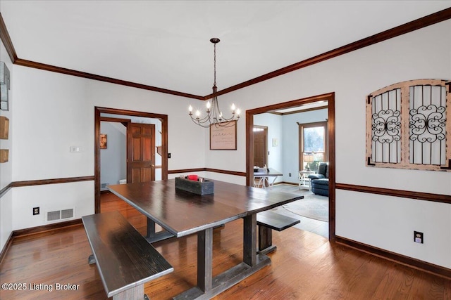 dining space with crown molding, dark hardwood / wood-style flooring, and an inviting chandelier