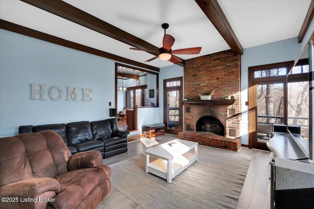 living room featuring a fireplace, beam ceiling, ceiling fan, and a healthy amount of sunlight