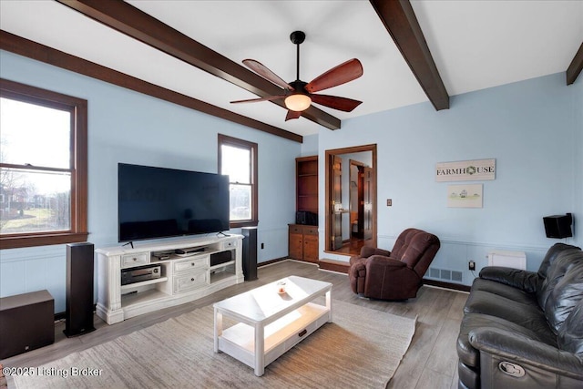 living room featuring hardwood / wood-style floors, ceiling fan, and beamed ceiling