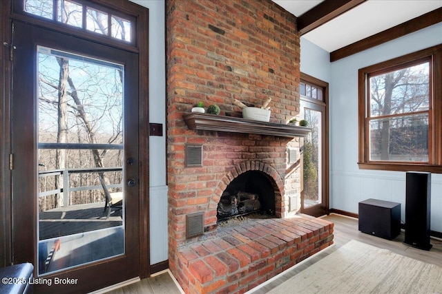 living room featuring beam ceiling, light wood-type flooring, and a fireplace