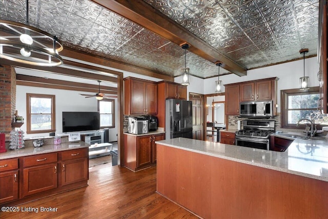 kitchen with hanging light fixtures, light stone countertops, sink, and appliances with stainless steel finishes