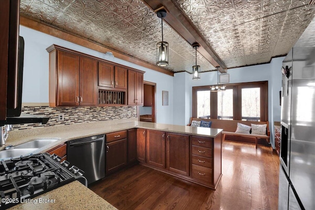 kitchen with kitchen peninsula, backsplash, stainless steel dishwasher, a chandelier, and hanging light fixtures