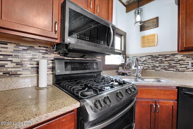 kitchen featuring light stone countertops, sink, backsplash, pendant lighting, and black appliances