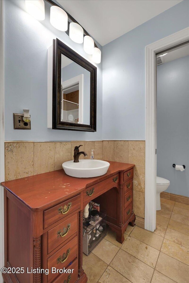 bathroom featuring tile patterned flooring, vanity, toilet, and tile walls