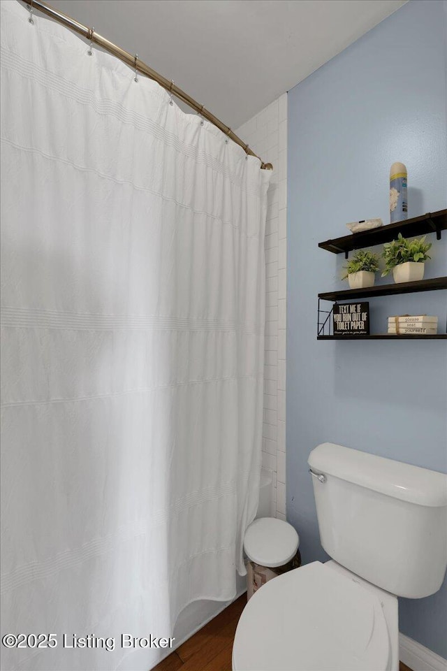 bathroom featuring shower / bath combo with shower curtain, toilet, and wood-type flooring