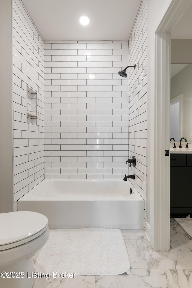 full bathroom featuring vanity, tiled shower / bath combo, and toilet