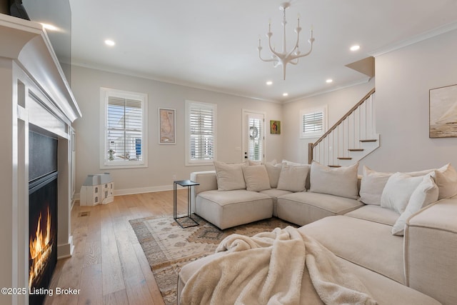 living room featuring a chandelier, light wood-type flooring, and ornamental molding