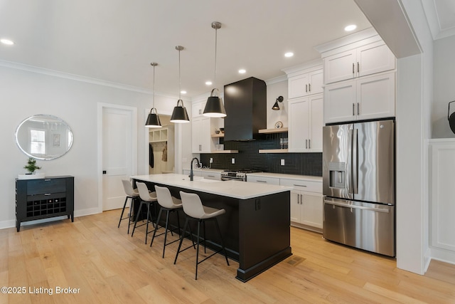 kitchen with a center island with sink, white cabinetry, stainless steel appliances, and exhaust hood