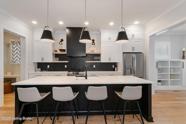 kitchen with white cabinets, appliances with stainless steel finishes, ventilation hood, and a center island with sink