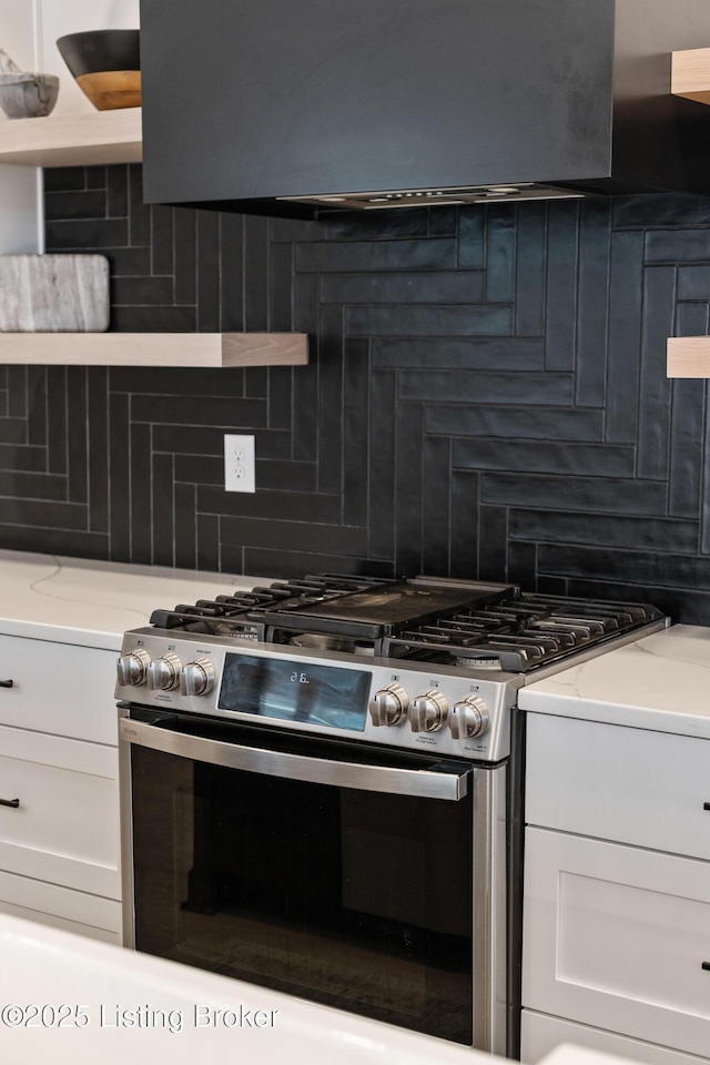 kitchen featuring decorative backsplash, ventilation hood, white cabinets, and high end stainless steel range oven