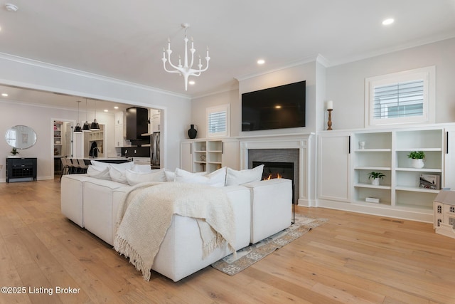 living room with crown molding, light hardwood / wood-style flooring, and an inviting chandelier