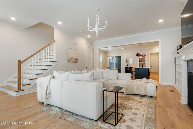 living room featuring a chandelier, light wood-type flooring, and ornamental molding