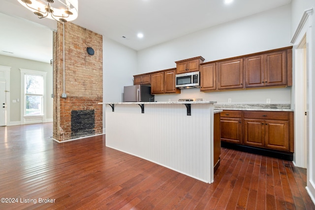 kitchen featuring a center island, a kitchen breakfast bar, dark hardwood / wood-style floors, a fireplace, and appliances with stainless steel finishes