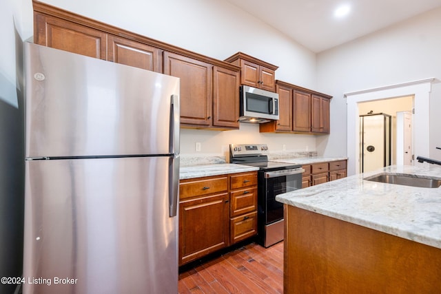 kitchen featuring light hardwood / wood-style floors, light stone counters, sink, and appliances with stainless steel finishes