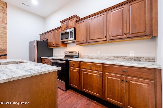 kitchen featuring light stone countertops, sink, stainless steel appliances, and wood-type flooring