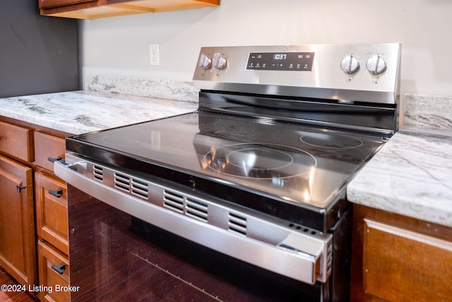 kitchen featuring stainless steel electric stove and light stone countertops