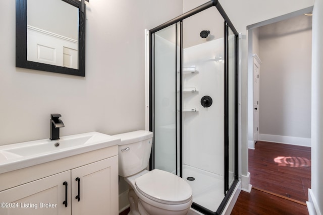 bathroom with wood-type flooring, vanity, toilet, and an enclosed shower