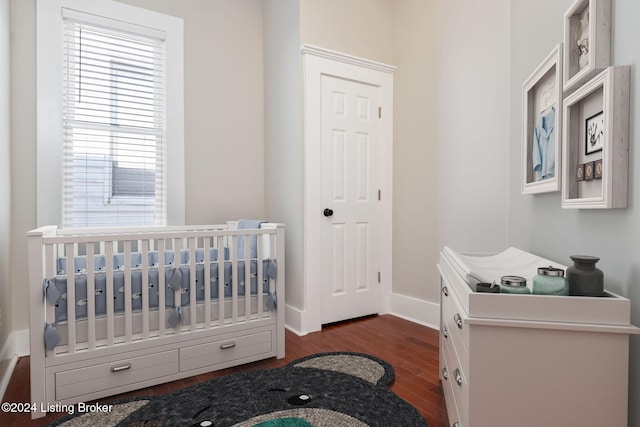 bedroom featuring dark hardwood / wood-style flooring and a nursery area