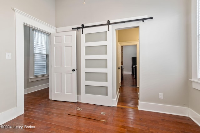 hallway featuring a barn door and dark hardwood / wood-style flooring