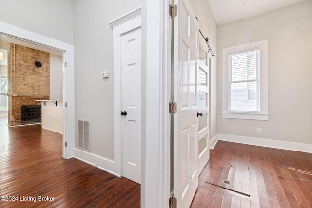 hallway with a barn door and dark hardwood / wood-style floors