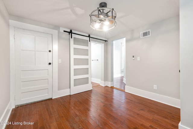 unfurnished bedroom with hardwood / wood-style floors, a barn door, and a closet