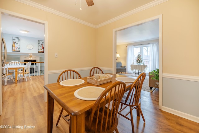 dining space with ceiling fan, light wood-type flooring, and ornamental molding