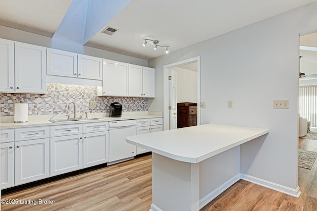 kitchen with kitchen peninsula, tasteful backsplash, white dishwasher, white cabinets, and sink