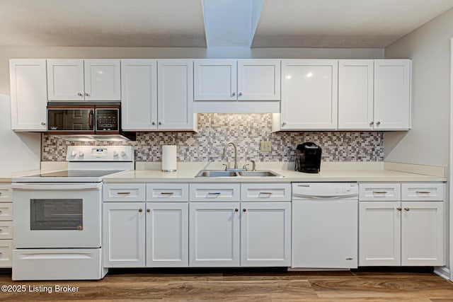 kitchen with sink, white appliances, white cabinetry, and backsplash