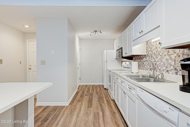 kitchen with sink, white cabinetry, white appliances, tasteful backsplash, and light hardwood / wood-style flooring