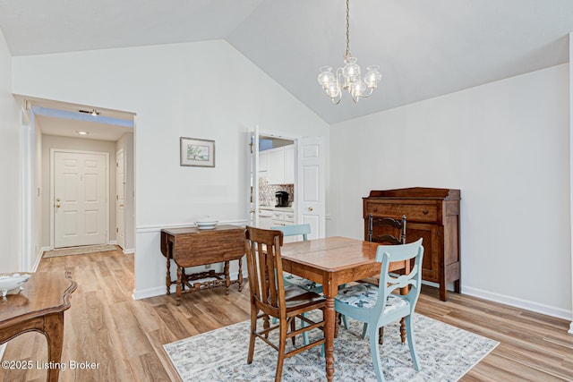 dining space with high vaulted ceiling, an inviting chandelier, and light wood-type flooring