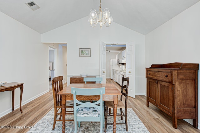 dining space featuring an inviting chandelier, vaulted ceiling, and light hardwood / wood-style flooring