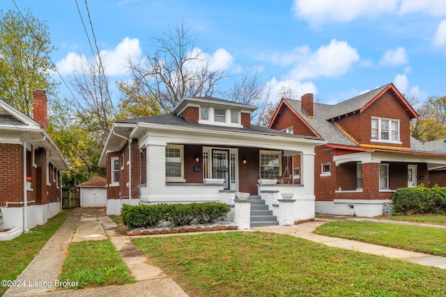 bungalow with covered porch, an outdoor structure, and a front yard