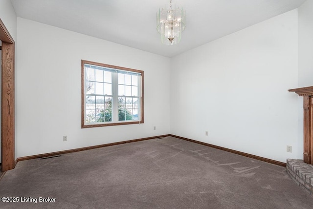 empty room featuring dark carpet and an inviting chandelier