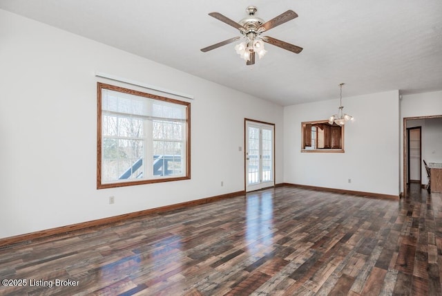 unfurnished living room with ceiling fan with notable chandelier and dark wood-type flooring