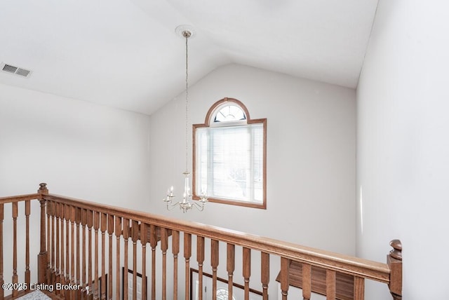 corridor with vaulted ceiling and an inviting chandelier