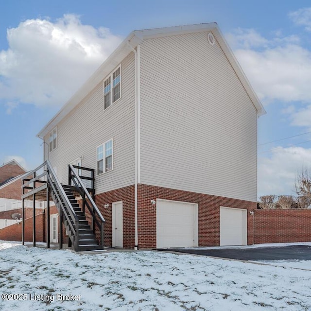 snow covered rear of property with a garage