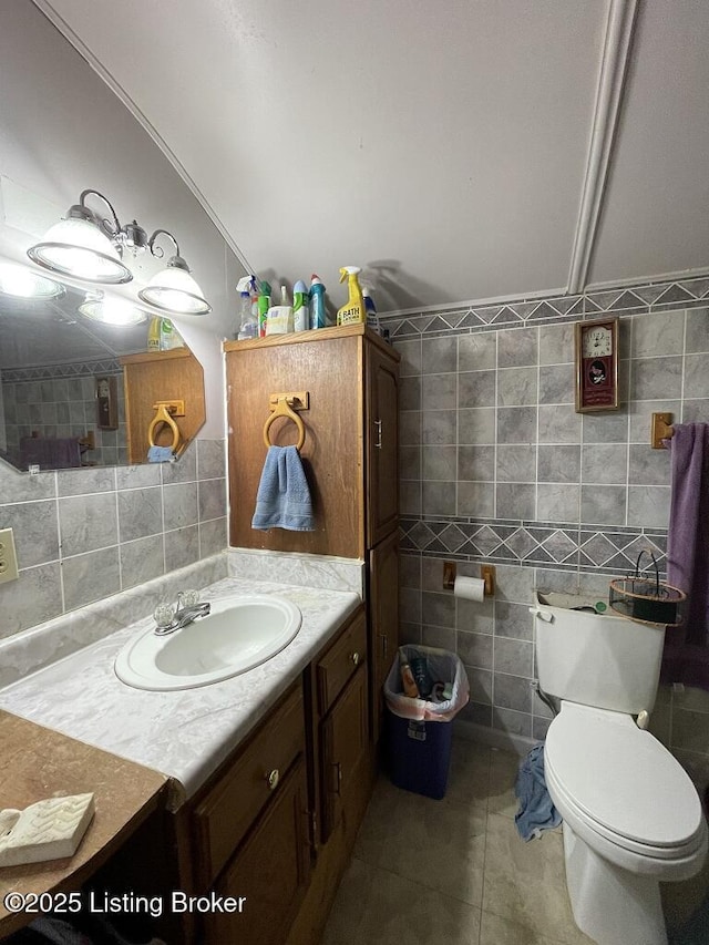 bathroom with tile patterned flooring, vanity, toilet, and tile walls