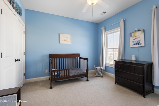 carpeted bedroom featuring ceiling fan, a crib, and a closet