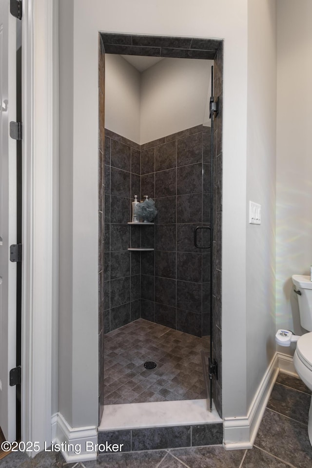 bathroom with a shower with shower door and toilet