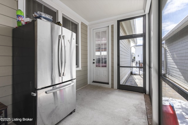 interior space featuring stainless steel fridge, a wealth of natural light, and wooden walls