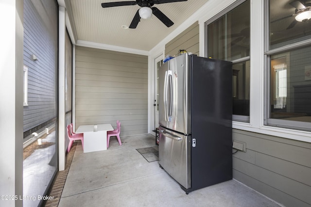 kitchen featuring ceiling fan, wooden walls, and stainless steel refrigerator