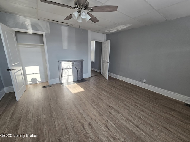 unfurnished bedroom with dark hardwood / wood-style floors, a closet, a drop ceiling, and ceiling fan