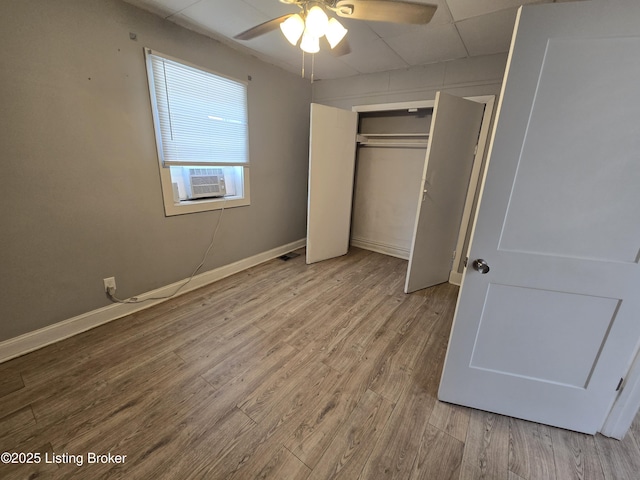 unfurnished bedroom featuring a closet, light hardwood / wood-style flooring, ceiling fan, and cooling unit