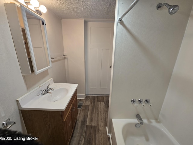 bathroom with shower / tub combination, vanity, wood-type flooring, and a textured ceiling