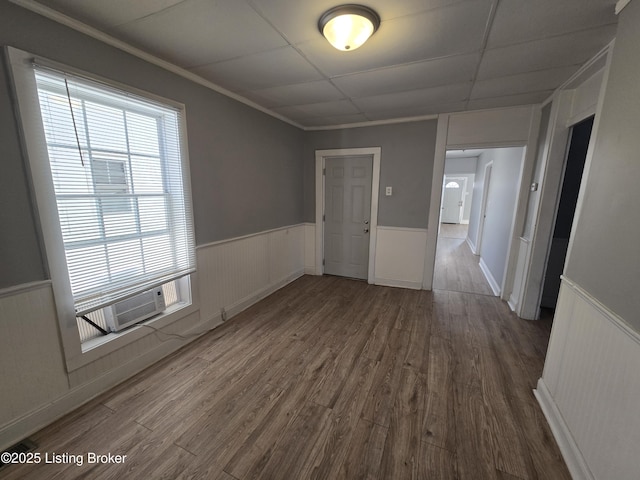 empty room with hardwood / wood-style flooring, a drop ceiling, and ornamental molding