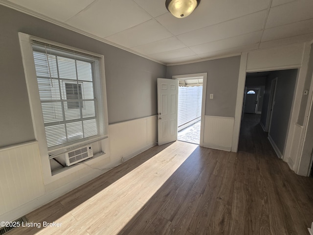 unfurnished room with cooling unit, dark wood-type flooring, and ornamental molding