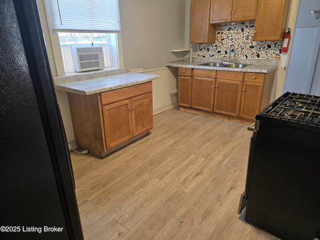 kitchen featuring light hardwood / wood-style floors, cooling unit, black appliances, and sink