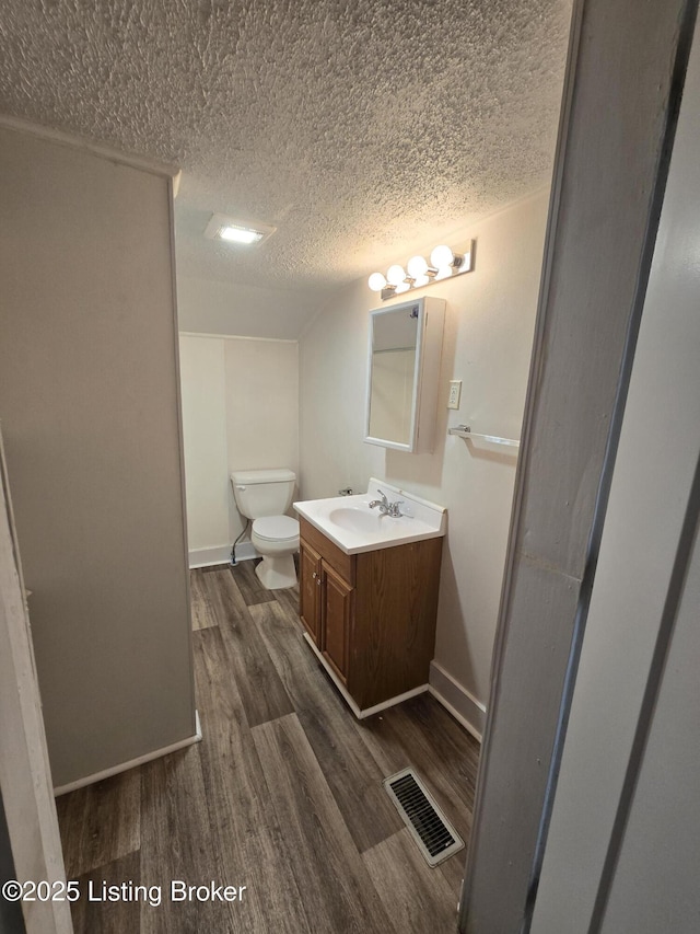 bathroom with hardwood / wood-style floors, vanity, a textured ceiling, and toilet