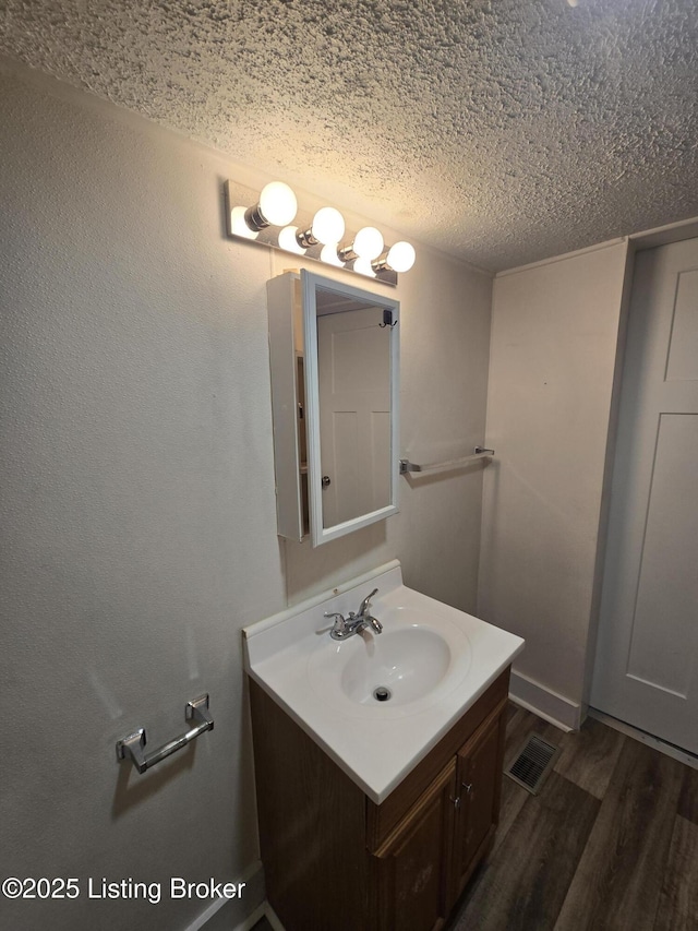 bathroom with wood-type flooring, vanity, and a textured ceiling