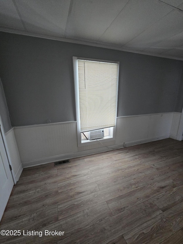 spare room featuring cooling unit, ornamental molding, and hardwood / wood-style flooring